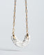 Gold paperclip chain necklace with hand-painted gray-and-white Talavera ceramic crescent pendant.