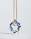 Gold chain necklace with hand‑painted blue‑and‑white Talavera open‑circle ceramic pendant.