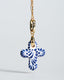 Gold chain necklace with hand‑painted blue‑and‑white Talavera ceramic cross pendant.